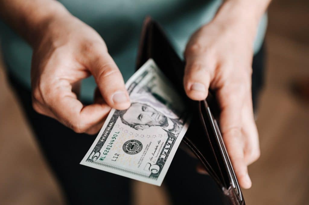 Man taking $5 bill out of his wallet.