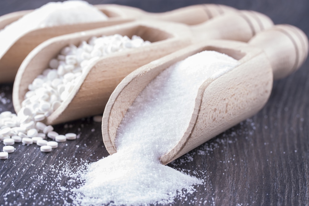 A line of sweeteners inside wooden scoops.