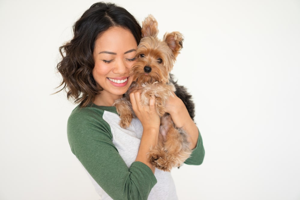A woman hugging and holding her dog as a new dog owner.