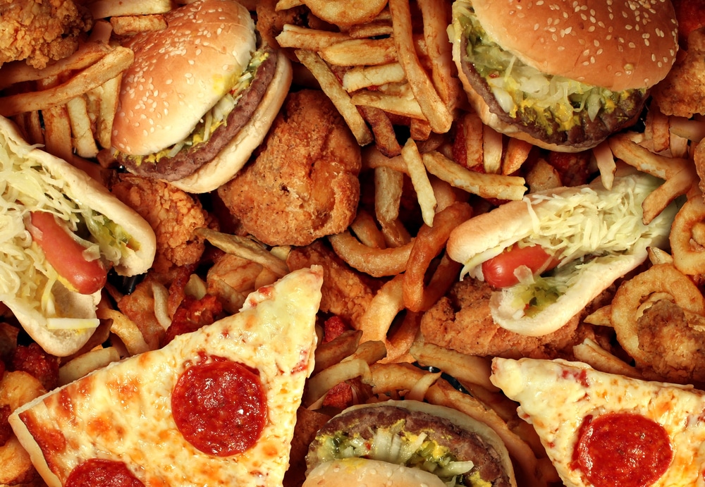 A closeup of junk food, including pizza and cheeseburgers.