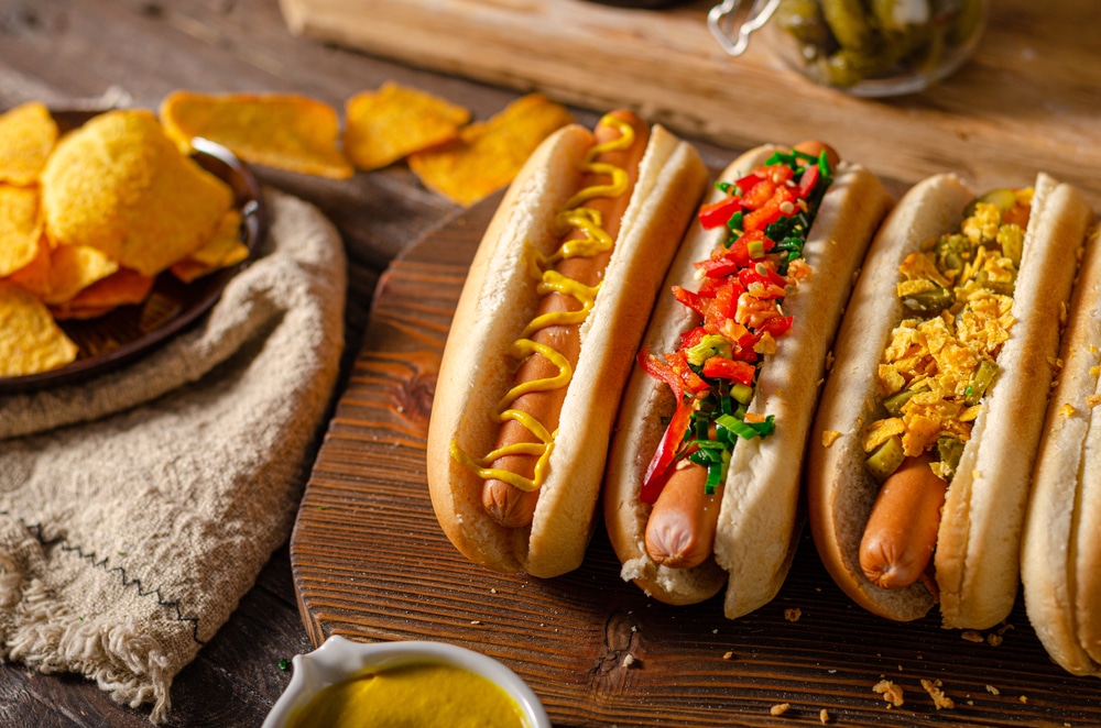 A closeup of some hot dogs with toppings and chips.