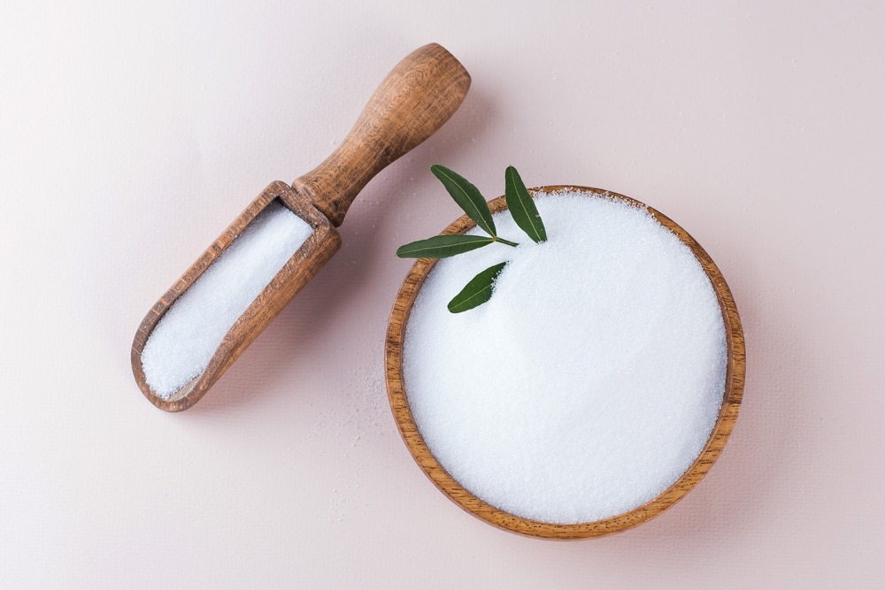 A top-down look at a bowl and scooper of erythritol.