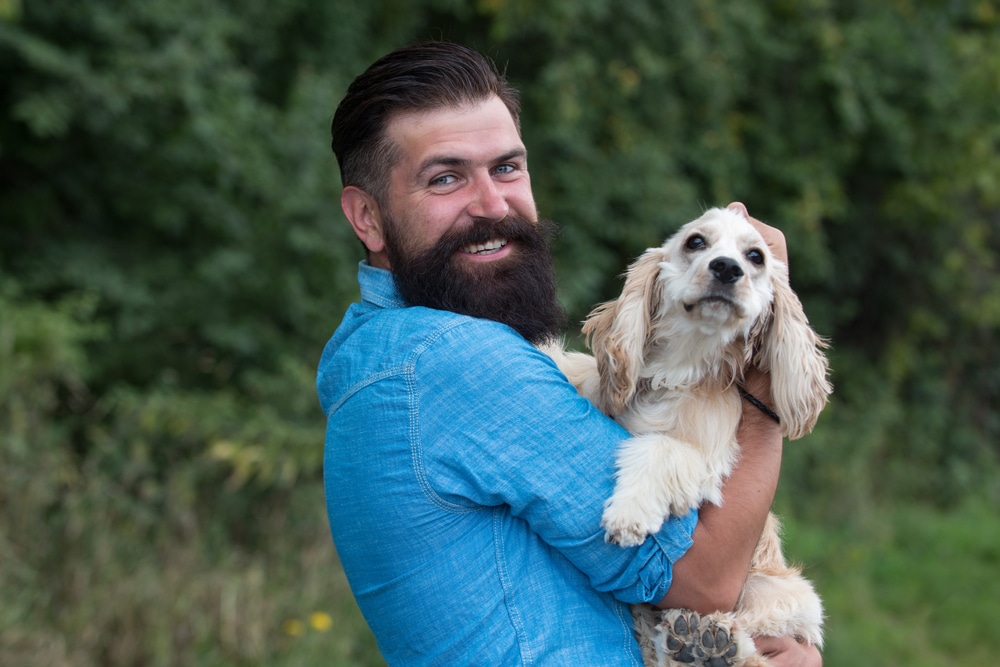 A man holding his dog and smiling.