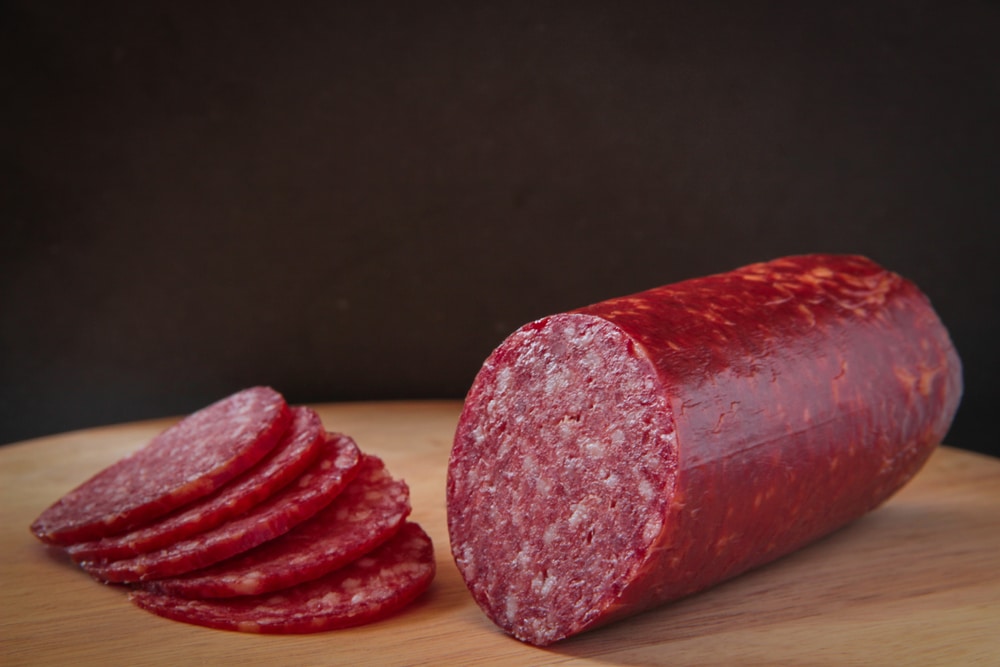 A closeup of salami and some salami slices on a cutting board.