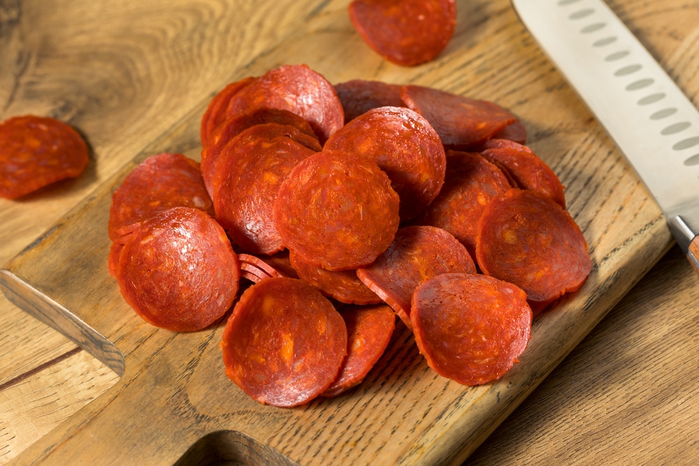 A pile of pepperoni on a cutting board.