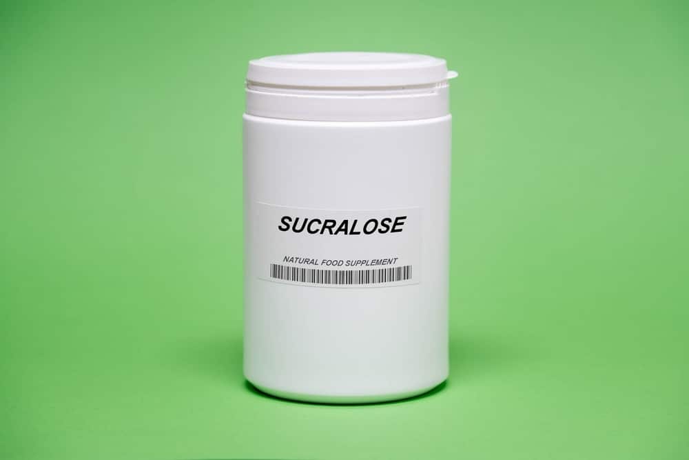 A bottle of sucralose against a green background.