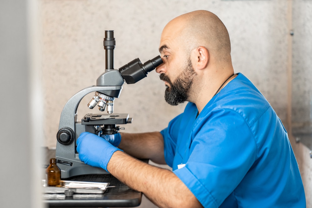 A side view of a vet looking through a microscope.