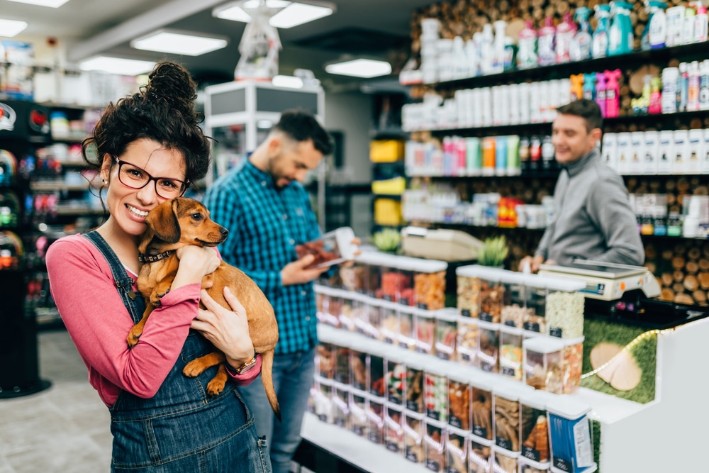 A woman in a pet store holding a dog.